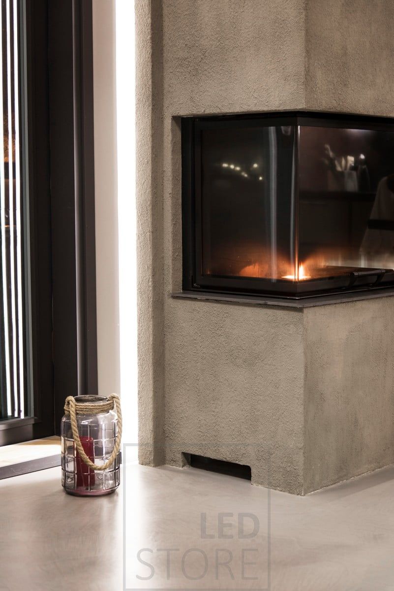 LED strip mounted behind the fireplace, indirectly illuminating through the wall and also highlighting the fireplace. Ledstore.fi